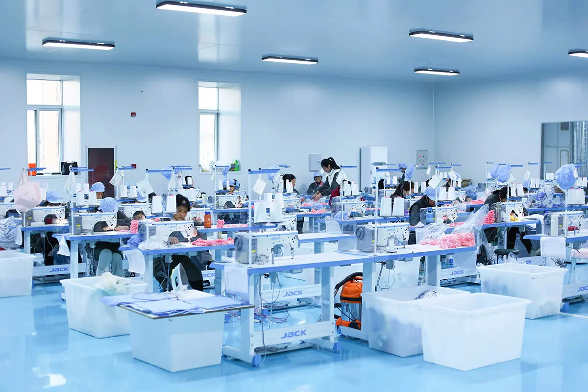 Wide view of WisePlush plush toy sewing workshop with workers and sewing machines
