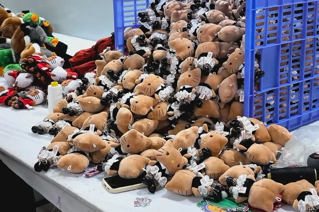 Cat plush keychains in a bulk basket for reorder and production consistency review