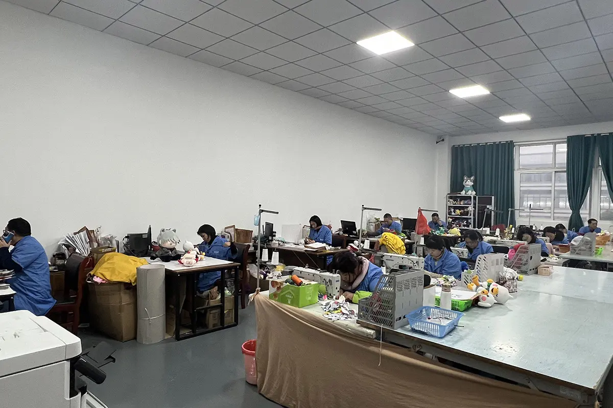 Plush sample sewing workshop with workers reviewing small custom plush pieces