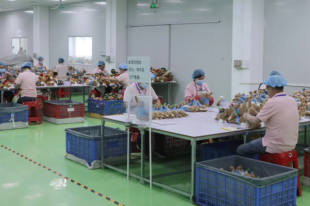 Worker checking the hanging loop attachment on a purple plush doll