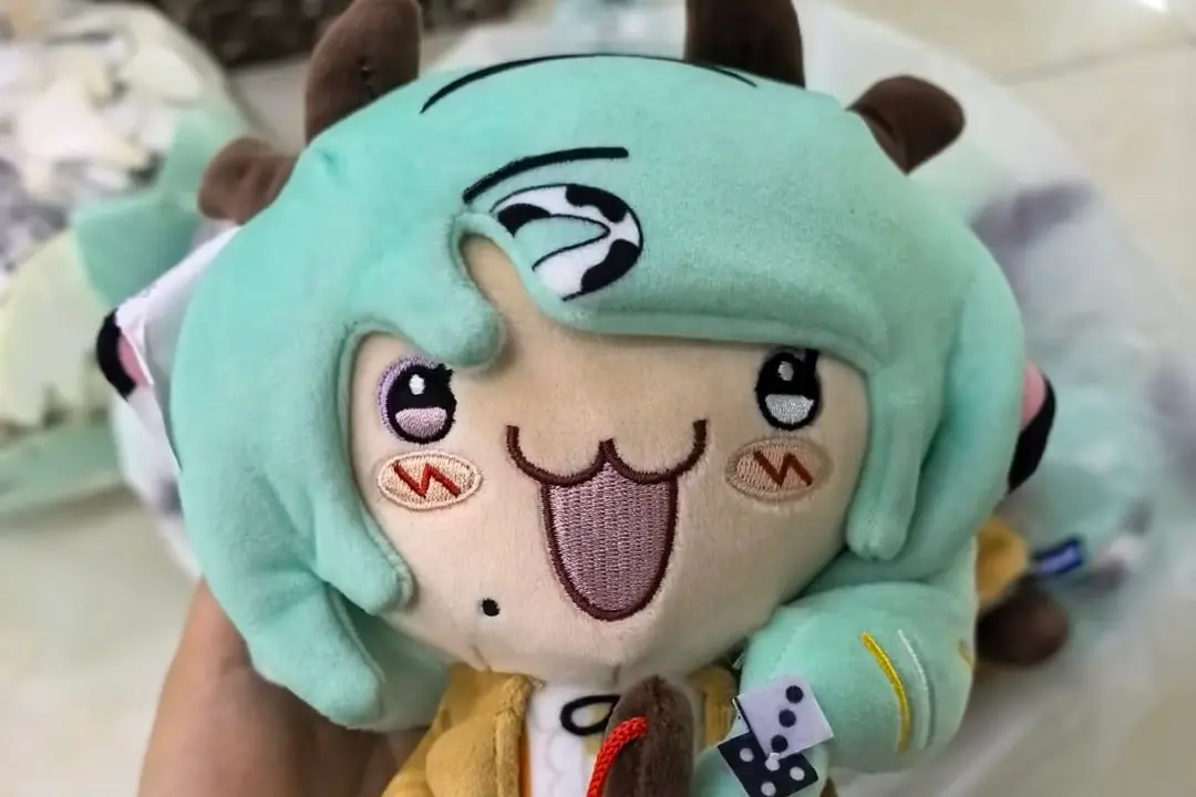 Close up of green hair character plush with embroidered eyes mouth and face details