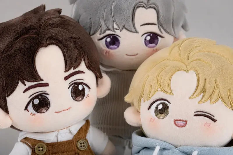 Close-up plush doll samples showing embroidered faces and layered hair details
