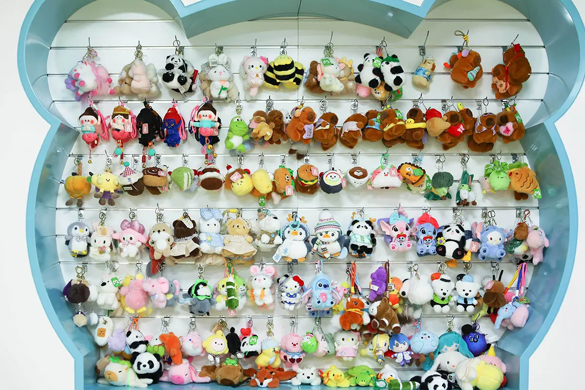 Wall display of many small plush keychain samples with clips and hang tags