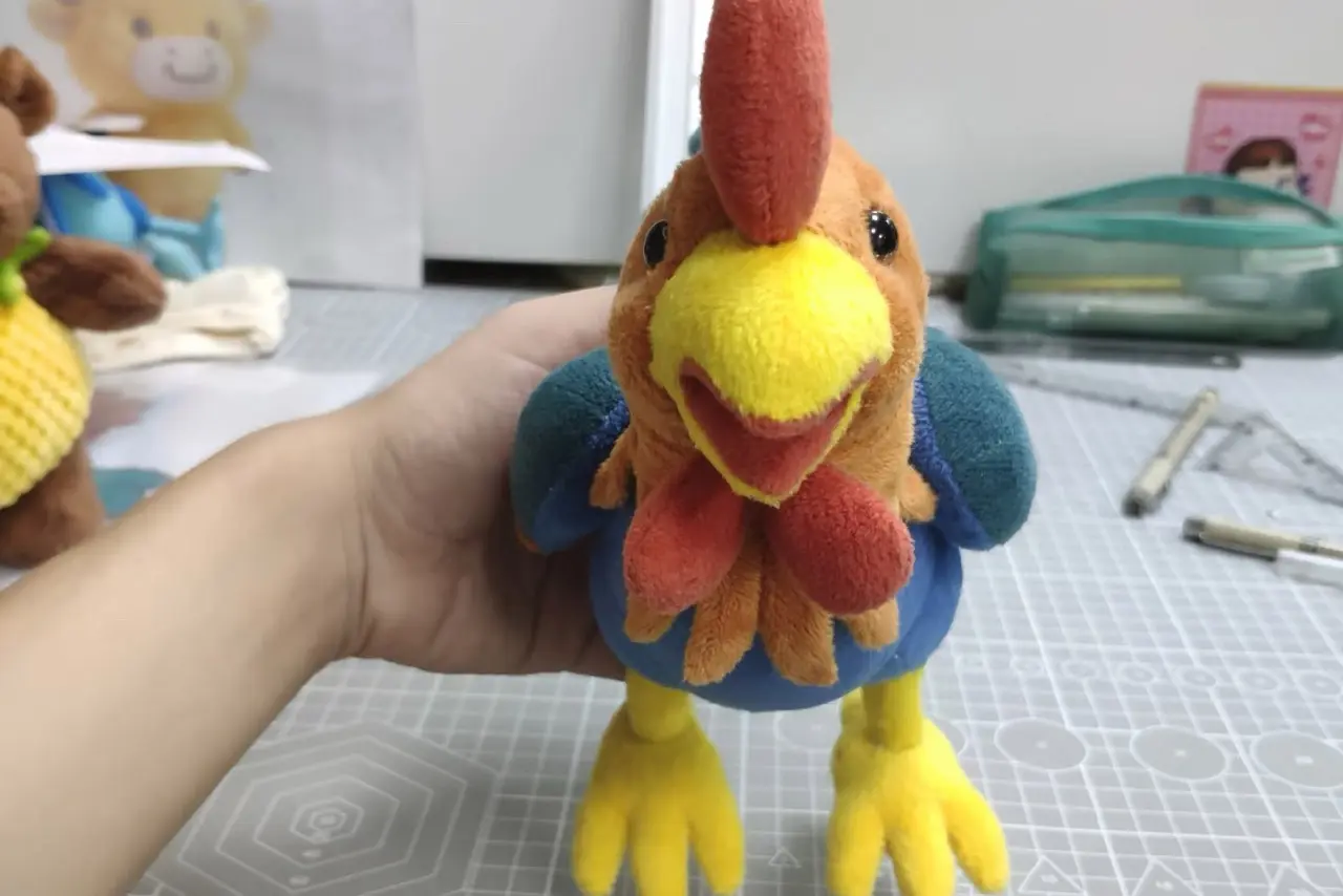 Handheld rooster stuffed animal sample showing fabric colors and face details