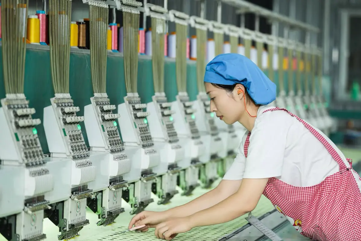 Factory worker checking embroidery machine setup for custom plush production