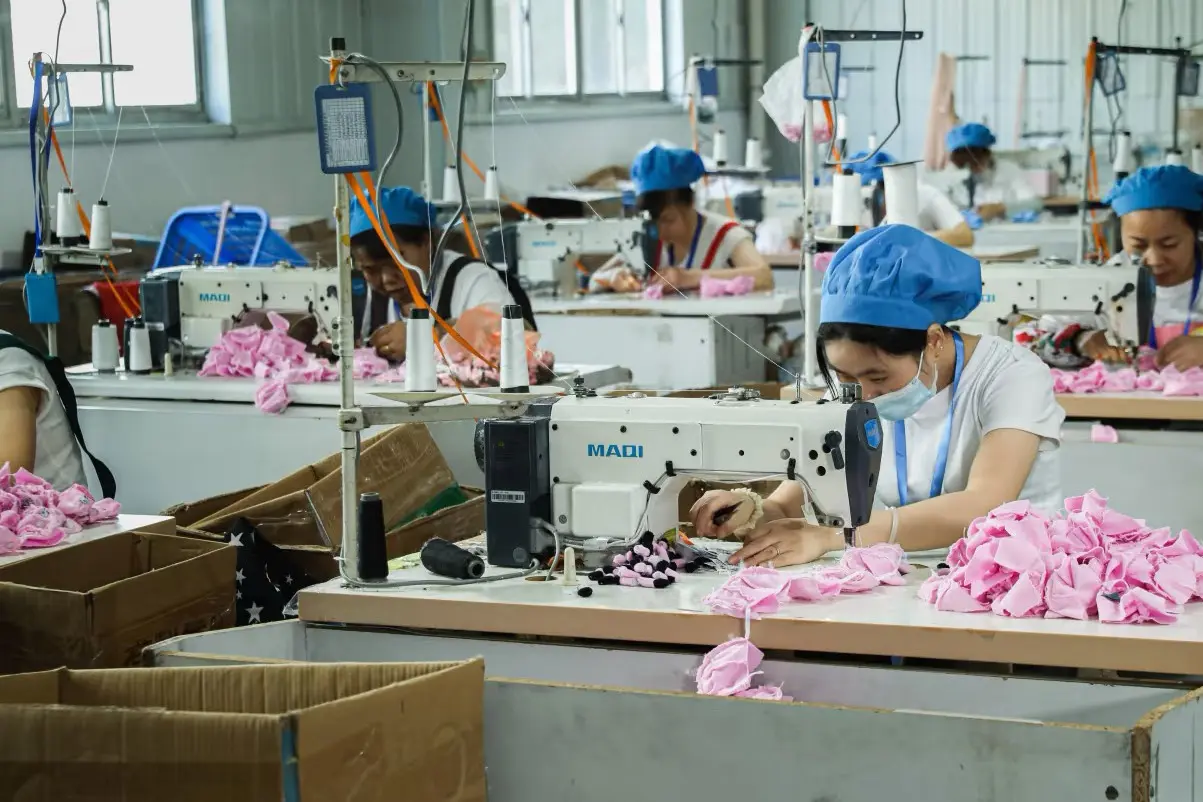 Pink plush fabric pieces being sewn on the factory sewing line