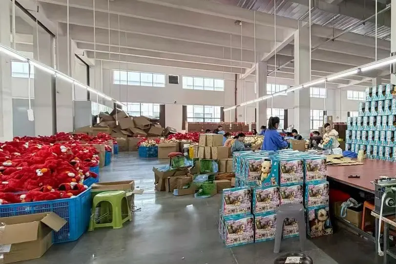 Plush toy box packaging area with retail boxes and bulk goods in the workshop