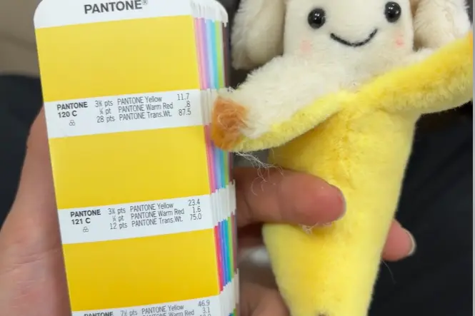 Banana plush sample checked against a Pantone color guide