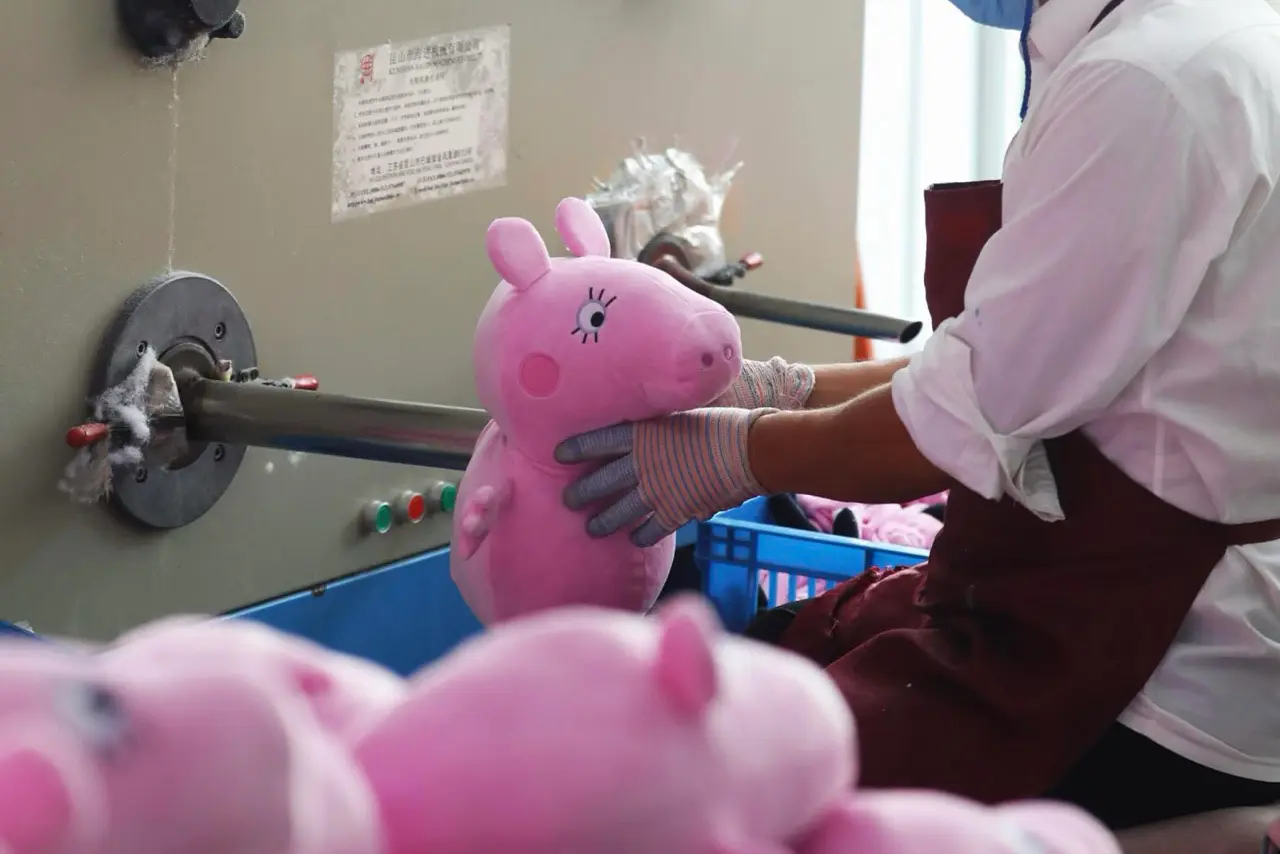 Worker checking a pink plush toy at the stuffing machine during sampling review
