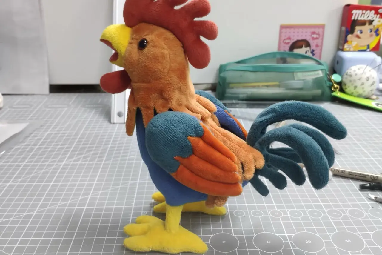 Rooster plush sample standing on a cutting mat for sample approval review