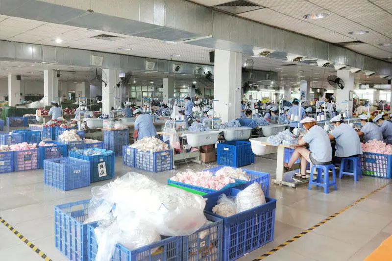 Factory workshop with workers sorting plush pieces in blue production baskets