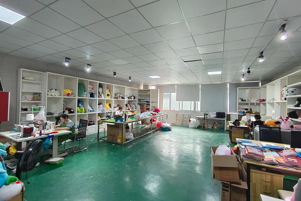 Plush doll sample room workshop with shelves, work tables, fabric, and plush samples