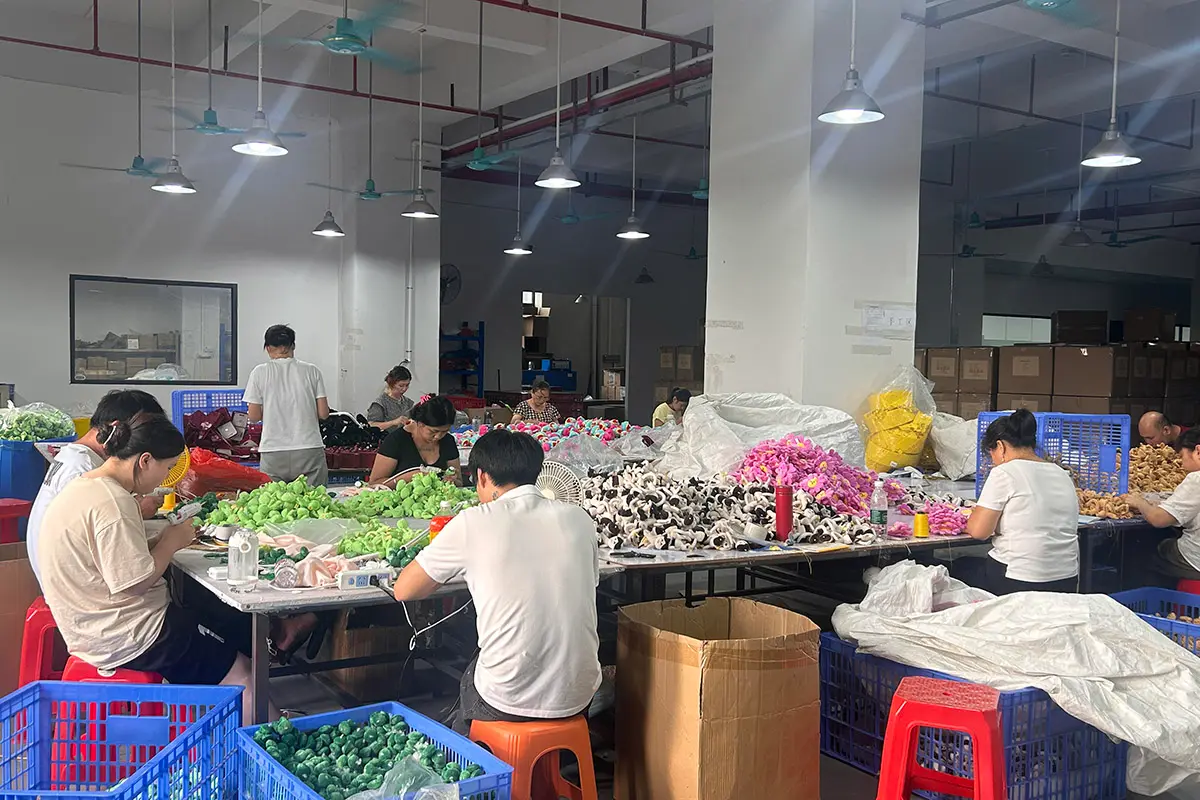 Factory workers assembling small plush keychains at workshop production tables