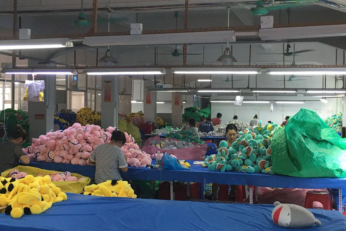 Stuffed animal factory production line with workers sorting and finishing plush toys